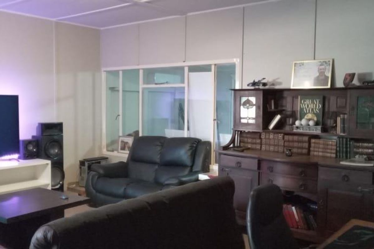 A living room featuring a large television, built-in cabinetry, and a glass-paneled partition wall, providing a functional and versatile living space.