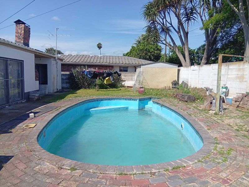 Outdoor pool area featuring a swimming pool with brick paving surround and boundary wall, requiring maintenance and landscaping updates.