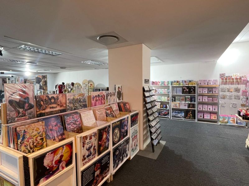 Interior view of a retail space featuring a central support column, suspended ceiling tiles, and recessed lighting throughout the open floor plan.