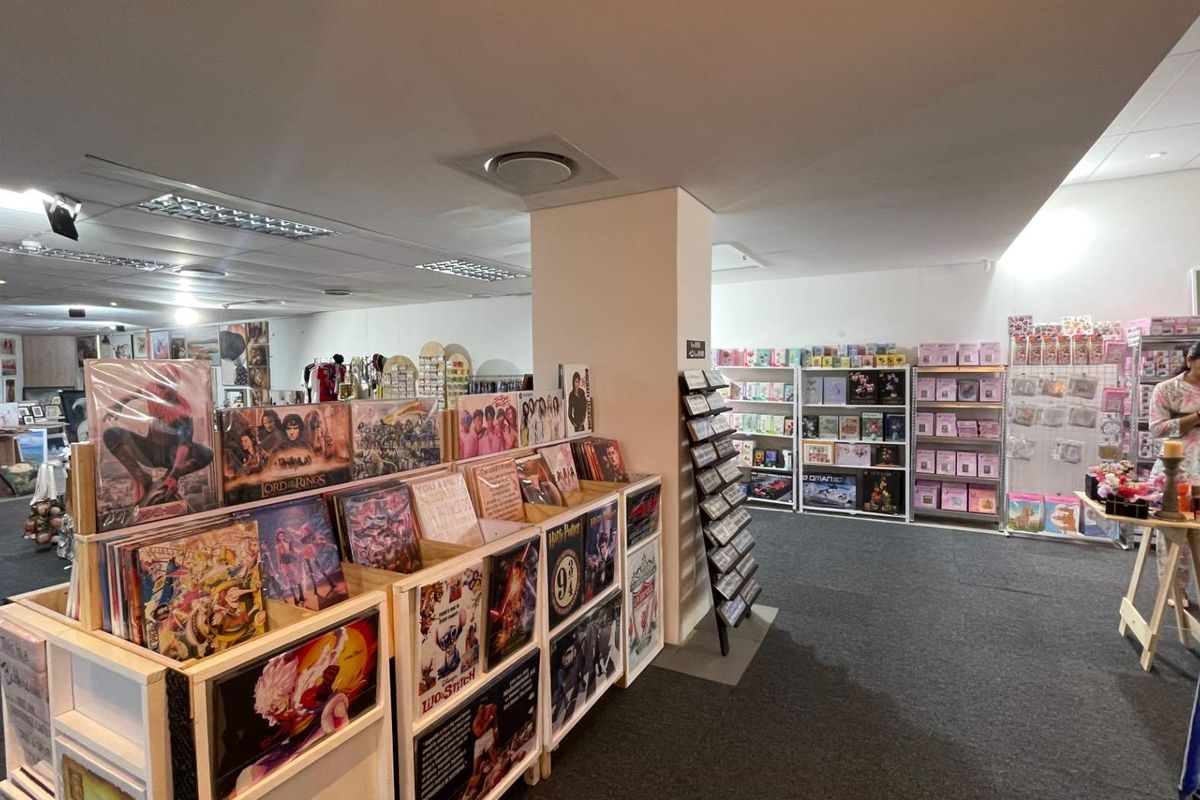 Interior view of a retail space featuring a central support column, suspended ceiling tiles, and recessed lighting throughout the open floor plan.