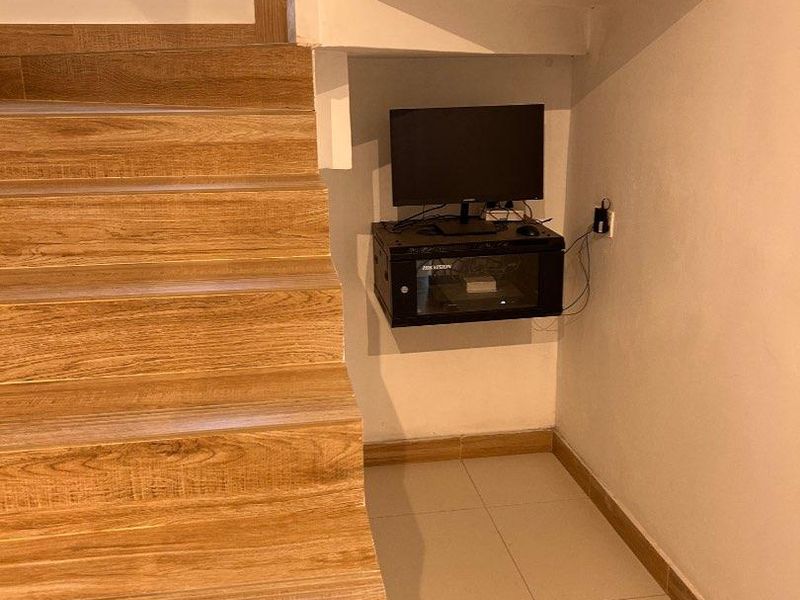 A hallway area featuring a staircase with wood-look tiling and a wall-mounted network cabinet tucked into the under-stair space.