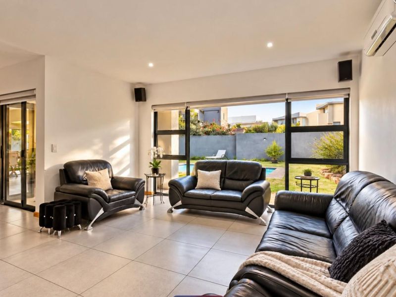 Spacious living room featuring large sliding glass doors that provide seamless access to the garden and pool area, complemented by modern tiled flooring.