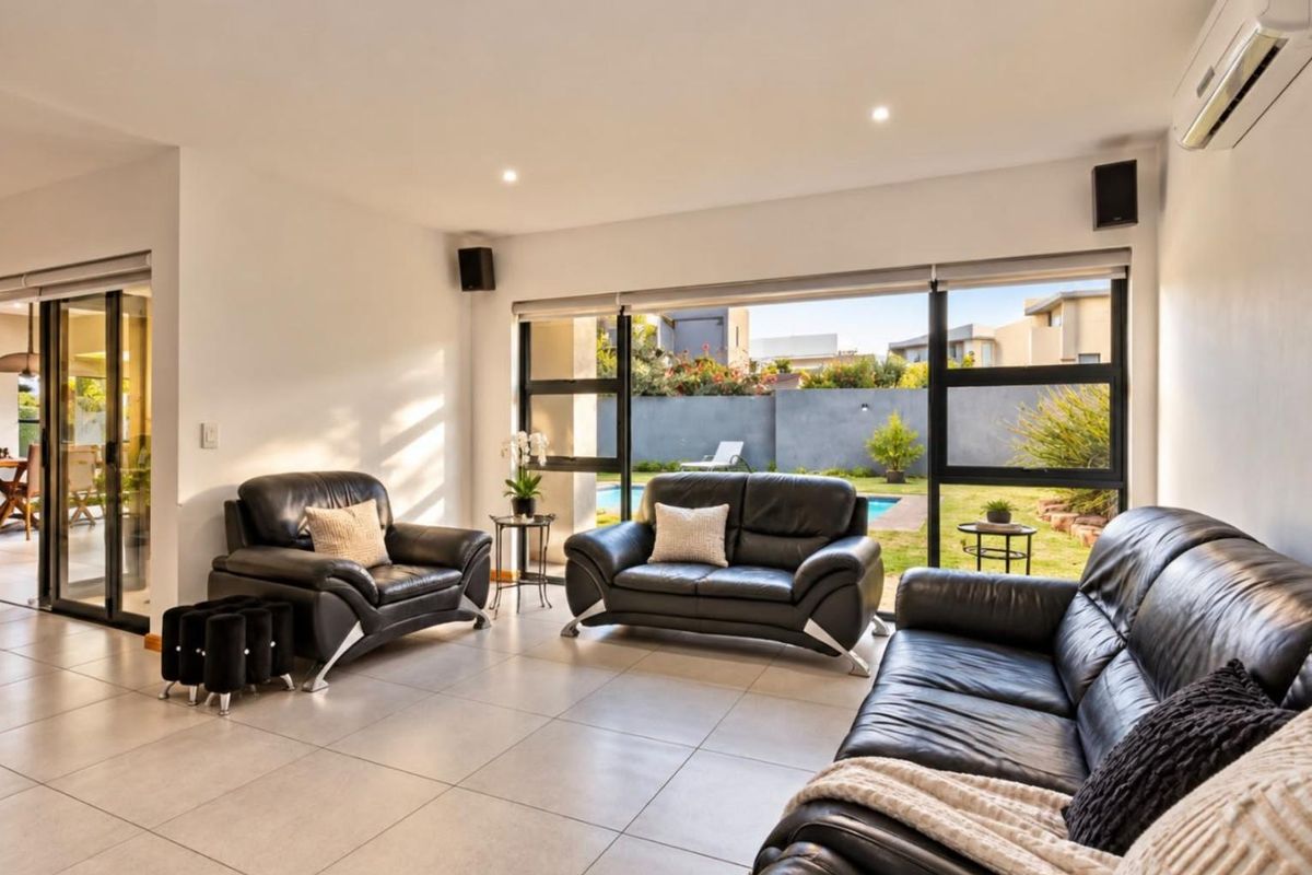 Spacious living room featuring large sliding glass doors that provide seamless access to the garden and pool area, complemented by modern tiled flooring.