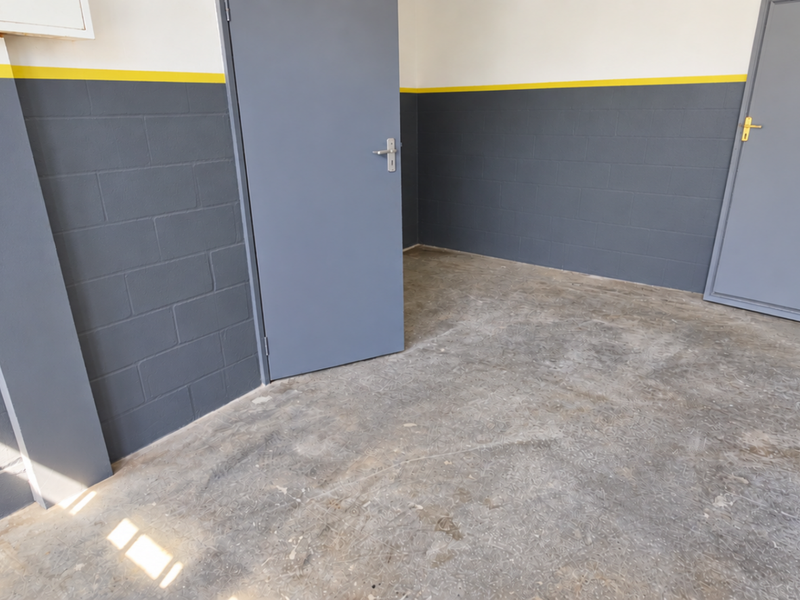 A clean, functional utility space featuring painted blockwork walls, concrete flooring, and essential safety equipment, suitable for storage or industrial use.