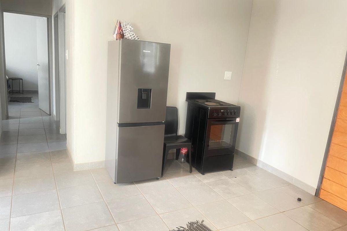 A simple kitchen area featuring tiled flooring and a freestanding stove, offering a functional space ready for personalization.