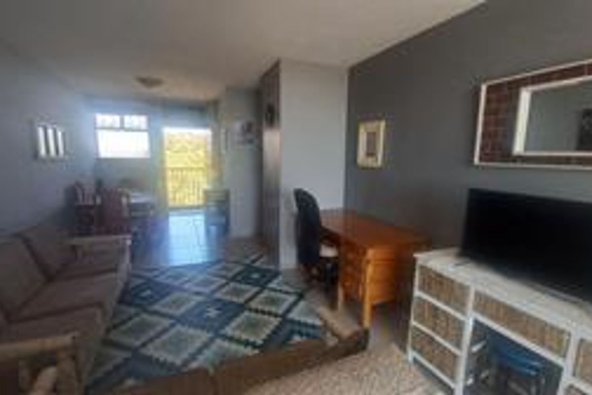 A living room area featuring dark grey walls, tiled flooring, and access to an adjoining balcony.