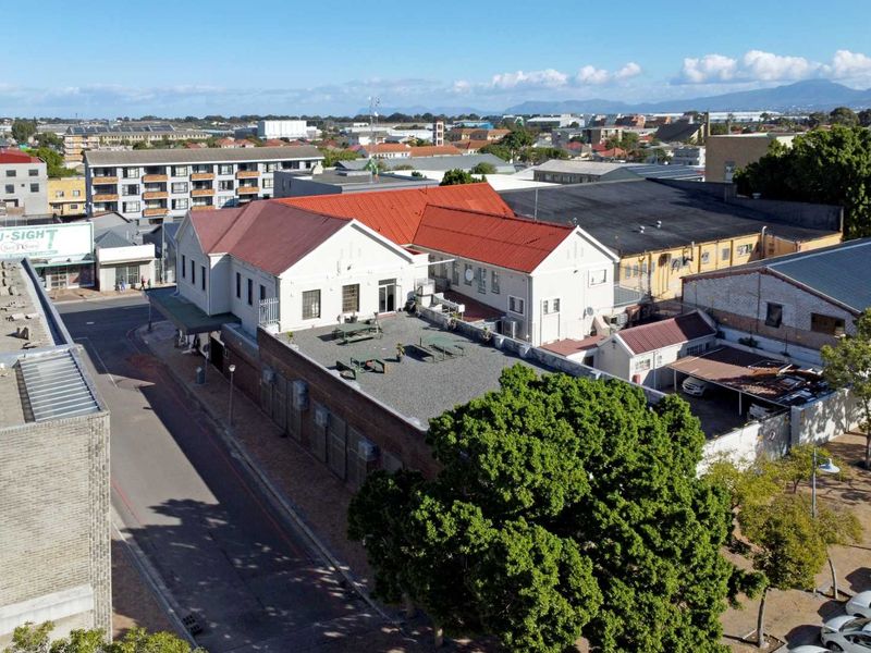 Aerial view of the property showing the building structure, pitched and flat roof sections, and surrounding urban neighborhood context.