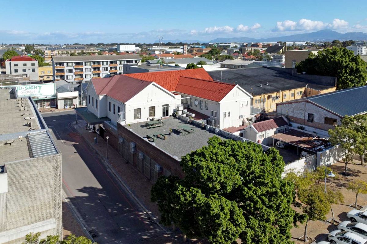 Aerial view of the property showing the building structure, pitched and flat roof sections, and surrounding urban neighborhood context.