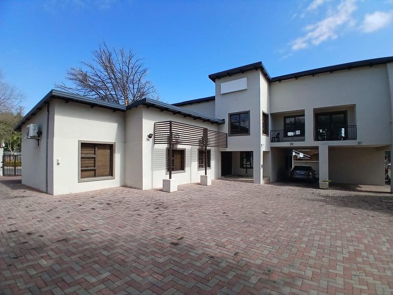 Front exterior view of a commercial property featuring a paved driveway, covered parking area, and a balcony with modern architectural finishes.