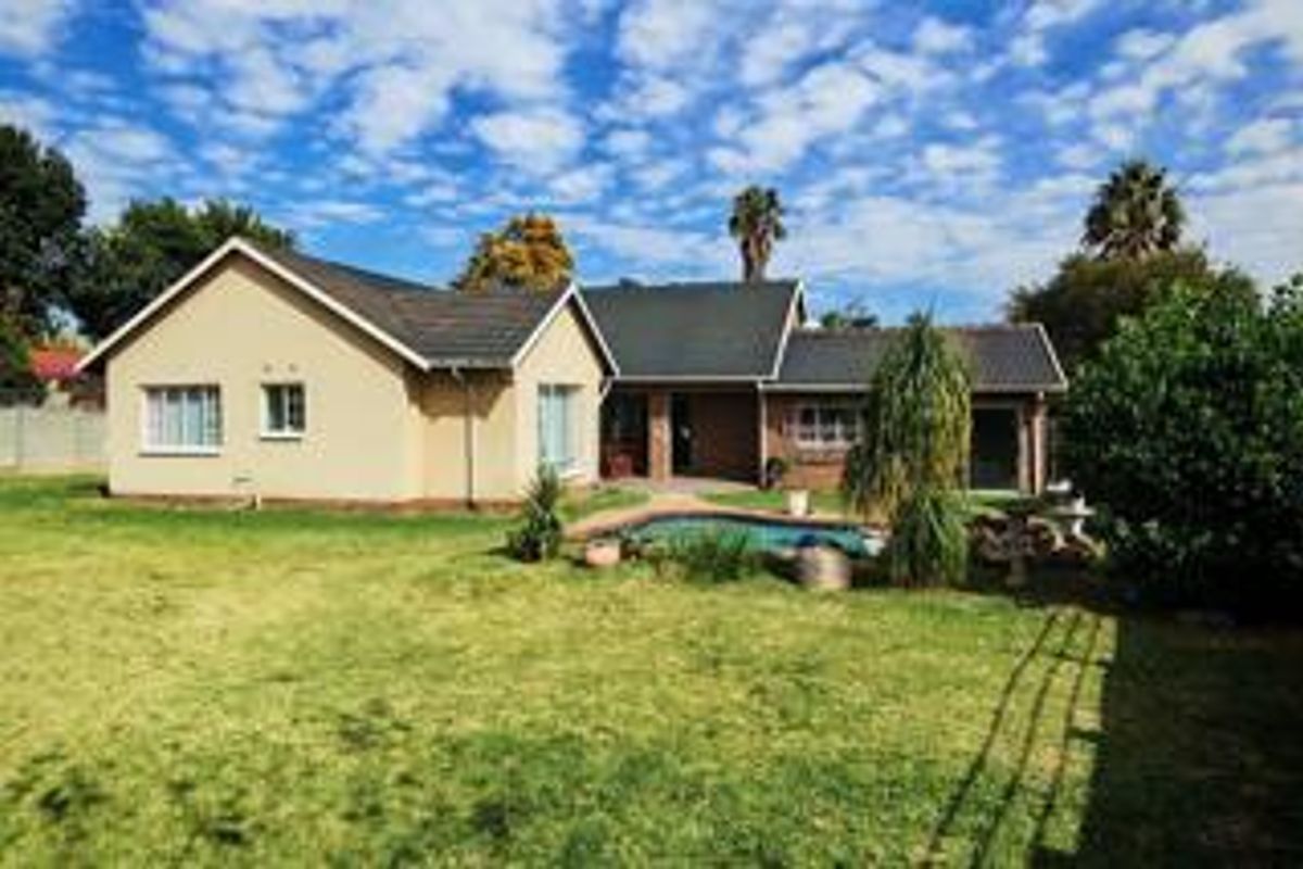 Rear view of the house featuring a swimming pool, paved patio area, and a spacious garden with a tiled roof structure.
