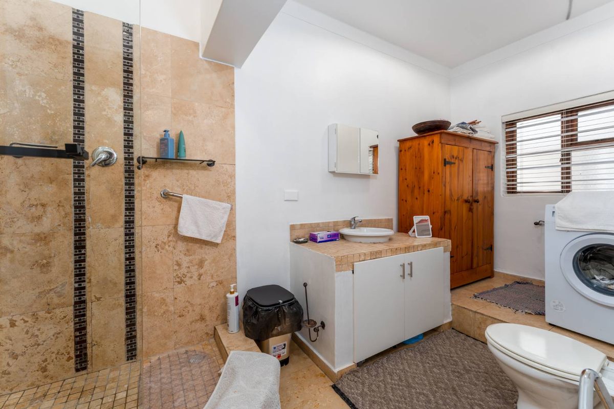 A functional bathroom featuring a tiled walk-in shower, a raised vanity area, and dedicated space for laundry appliances.
