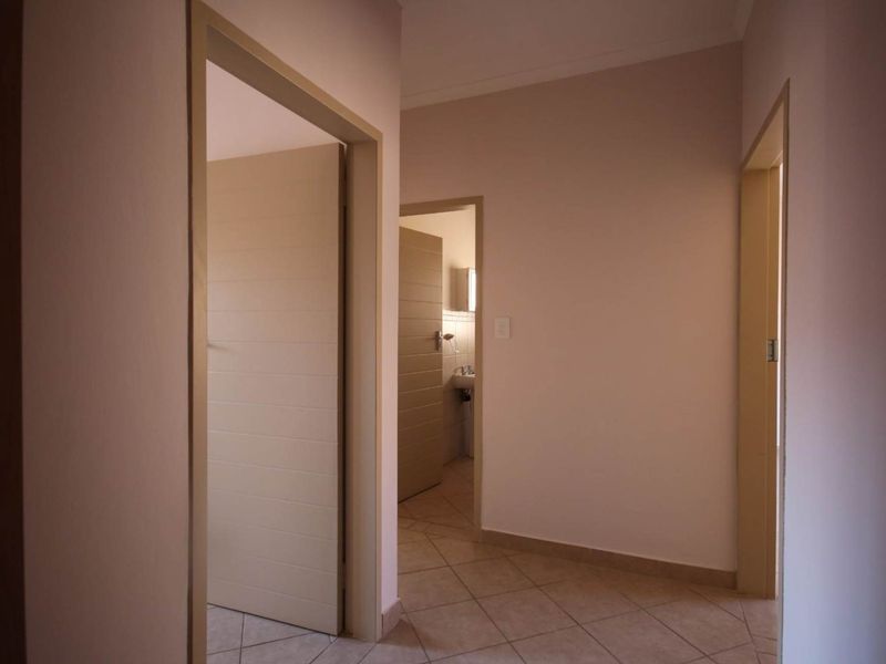 A clean, neutral-toned hallway featuring tiled flooring and access to multiple rooms within the apartment.