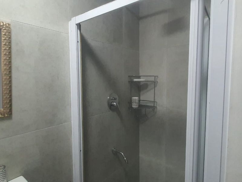 A modern bathroom featuring a tiled shower enclosure with a glass door and contemporary wall finishes.