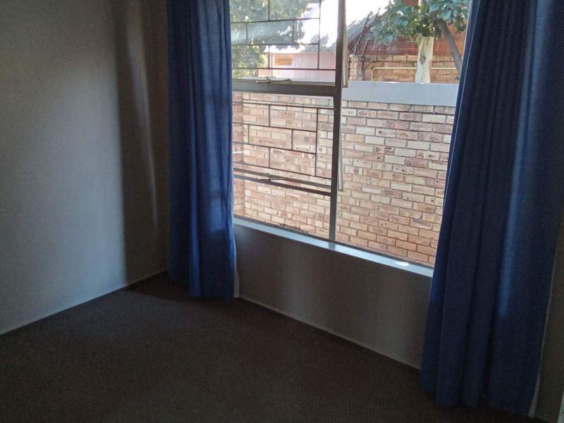 An empty bedroom featuring a window with security bars, providing a blank canvas for potential interior design updates.