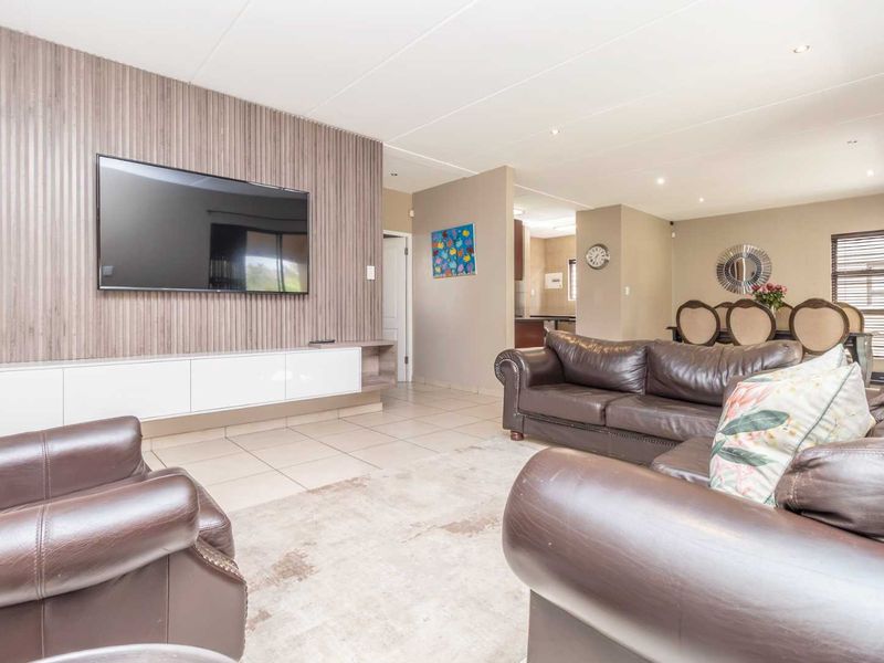 Spacious open-plan living area featuring tiled floors, recessed lighting, and a modern slatted feature wall with a built-in media console.