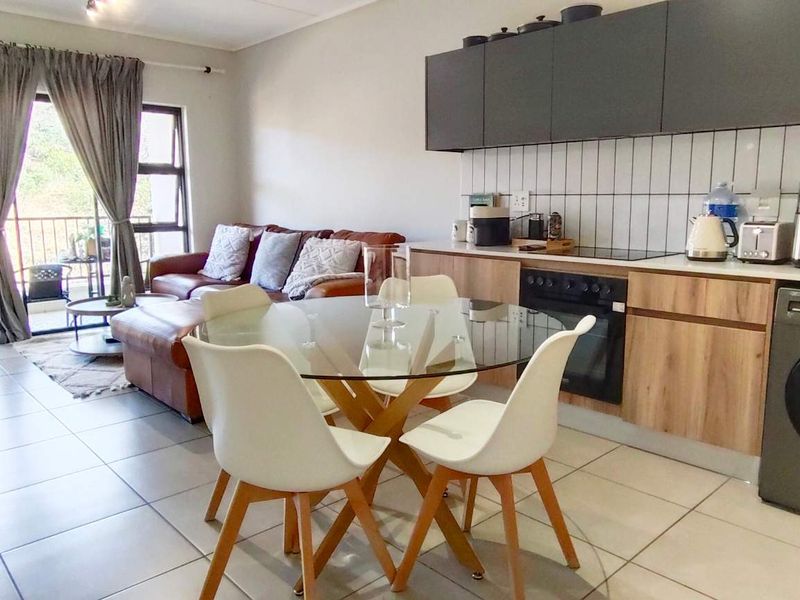 Modern open-plan living area featuring a contemporary kitchen with sleek cabinetry, tiled flooring, and direct access to a private balcony.