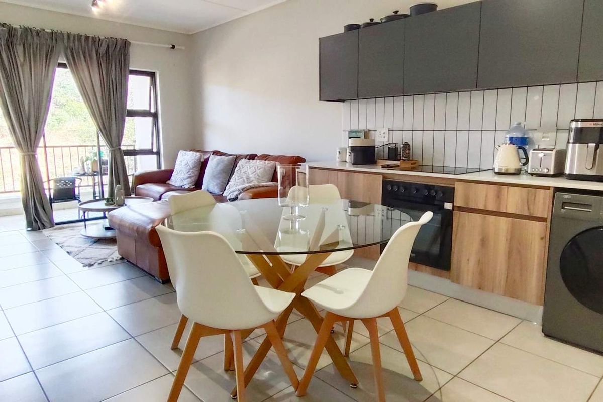 Modern open-plan living area featuring a contemporary kitchen with sleek cabinetry, tiled flooring, and direct access to a private balcony.