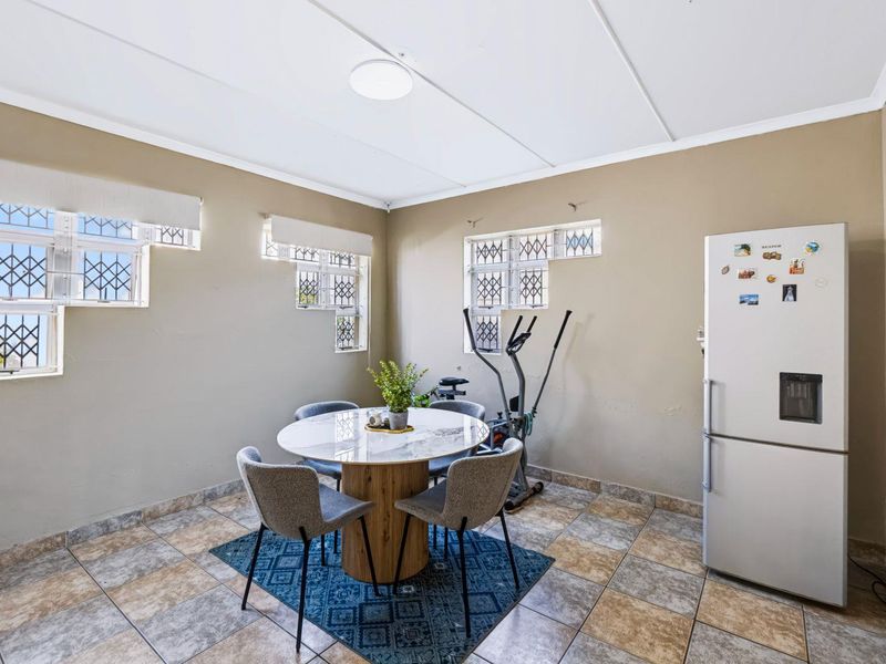 A dining area featuring tiled flooring and multiple windows fitted with security bars, offering a functional space for meals.