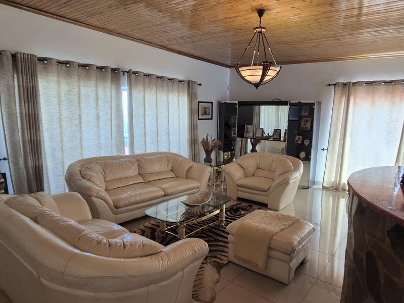 Spacious living room featuring a warm timber tongue and groove ceiling, tiled flooring, and a built-in bar area with feature stone cladding.