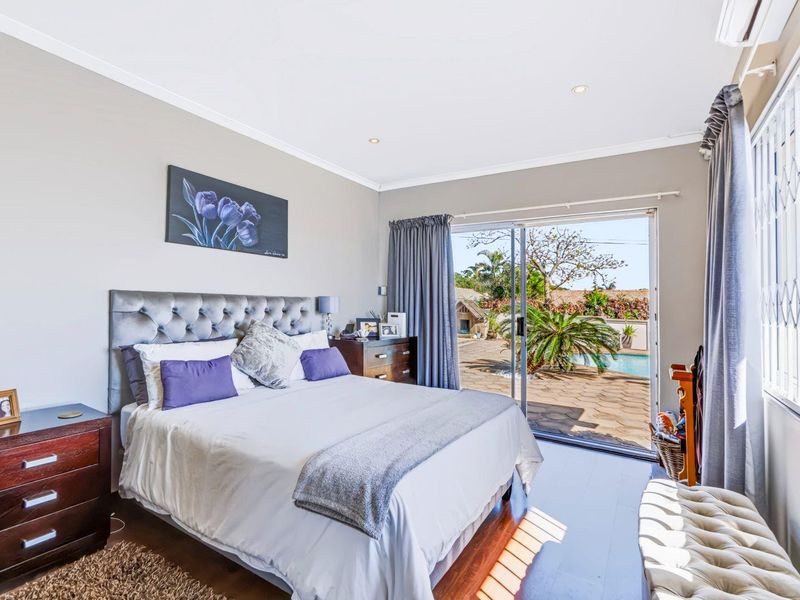 Spacious bedroom featuring laminate flooring, air conditioning, and large sliding glass doors providing direct access to the outdoor patio and pool area.