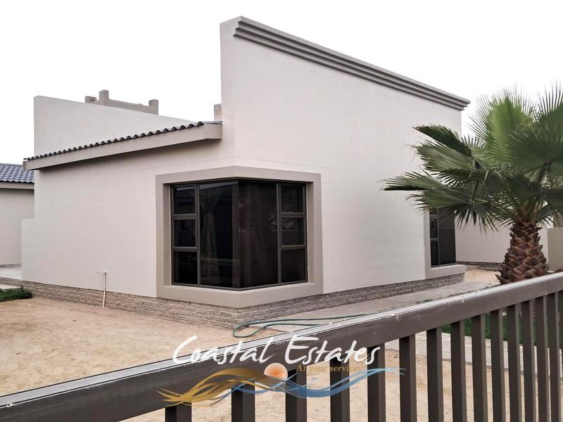 Rear view of a modern house featuring clean rendered walls, stone cladding base, and large corner windows.