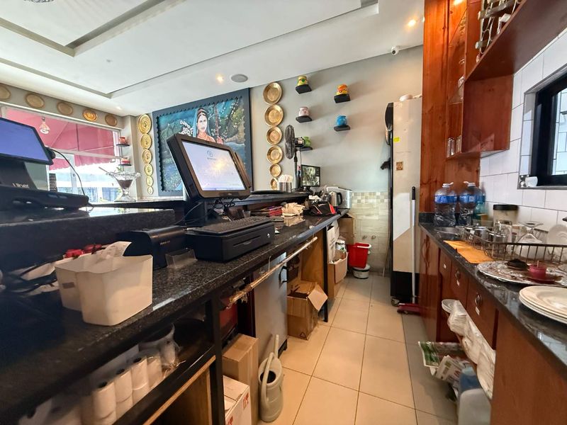 A functional commercial kitchen service area featuring granite countertops, built-in wooden cabinetry, and tiled flooring, suitable for restaurant operations.