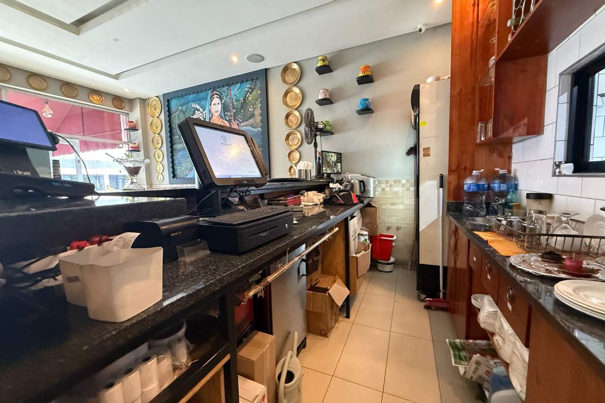A functional commercial kitchen service area featuring granite countertops, built-in wooden cabinetry, and tiled flooring, suitable for restaurant operations.