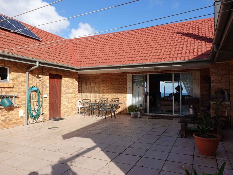 A spacious rear patio area featuring brick walls, tiled flooring, and sliding glass door access to the interior living space.
