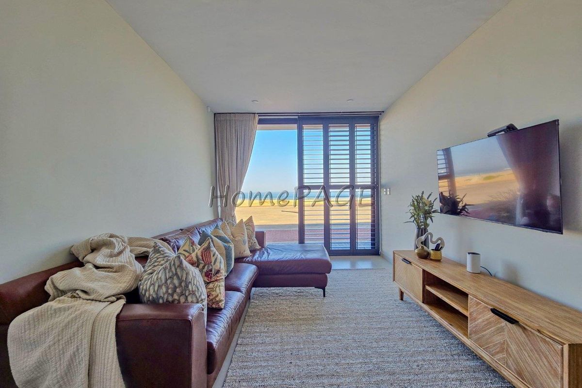 A bright living room featuring recessed downlights and large sliding glass doors with plantation shutters, offering natural light and access to the outdoors.
