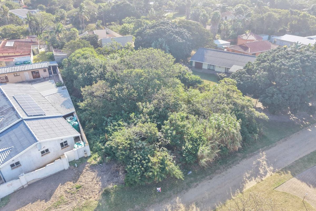 An aerial view of a vacant residential plot featuring dense mature trees and vegetation, situated within an established suburban neighborhood.