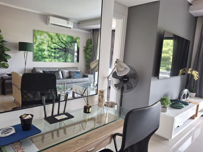 A modern living area featuring tiled flooring, a wall-mounted air conditioning unit, and a large feature mirror reflecting the space.