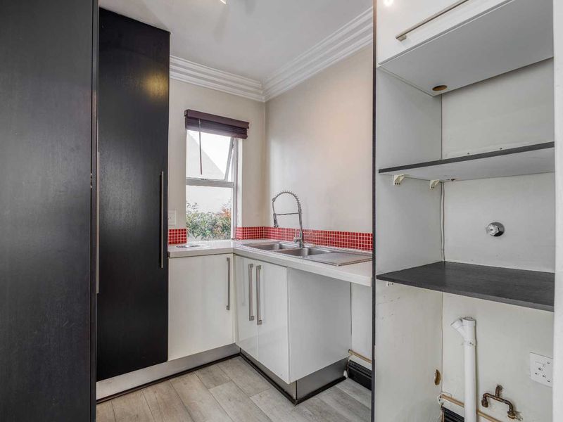 A functional laundry area featuring built-in cabinetry, a stainless steel sink with a gooseneck faucet, and dedicated plumbing connections for appliances.