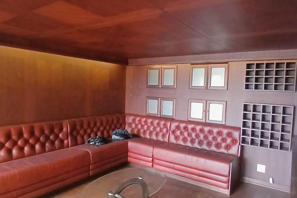 A sophisticated living area featuring extensive wood paneling, built-in leather bench seating, integrated cabinetry, and a dedicated wine storage rack.