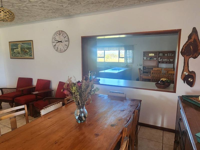 Open plan dining and living area featuring tiled flooring, an arched doorway to storage, and a serving hatch connecting to the kitchen.