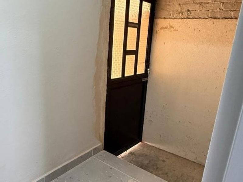 An entry area featuring tiled flooring and an external door, currently requiring finishing work on the surrounding wall plaster and trim.