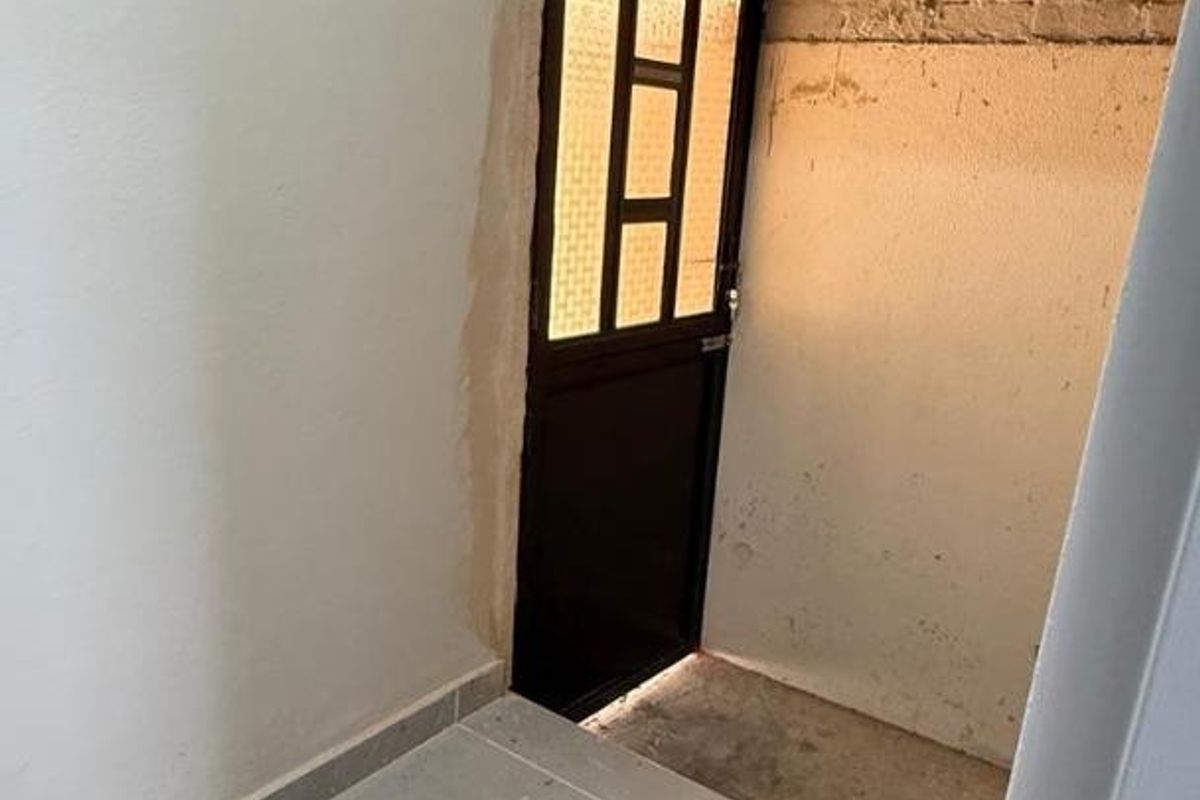An entry area featuring tiled flooring and an external door, currently requiring finishing work on the surrounding wall plaster and trim.