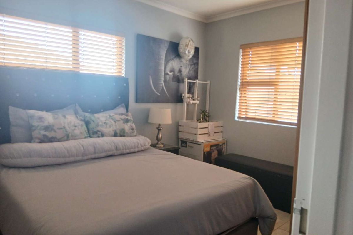 A well-lit bedroom featuring tiled flooring and wooden venetian blinds, providing a comfortable and functional living space.