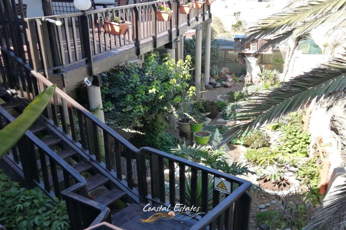 An elevated view of a rear garden area featuring a multi-level wooden deck with balustrades and stairs leading down to the landscaped outdoor space.