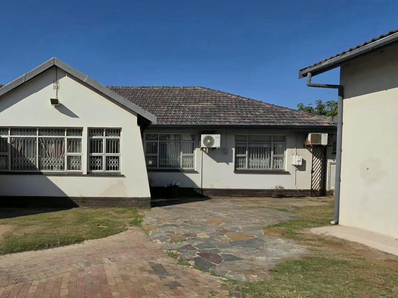 Rear view of the property featuring a tiled roof, paved walkway, and exterior wall finishes with visible signs of wear.