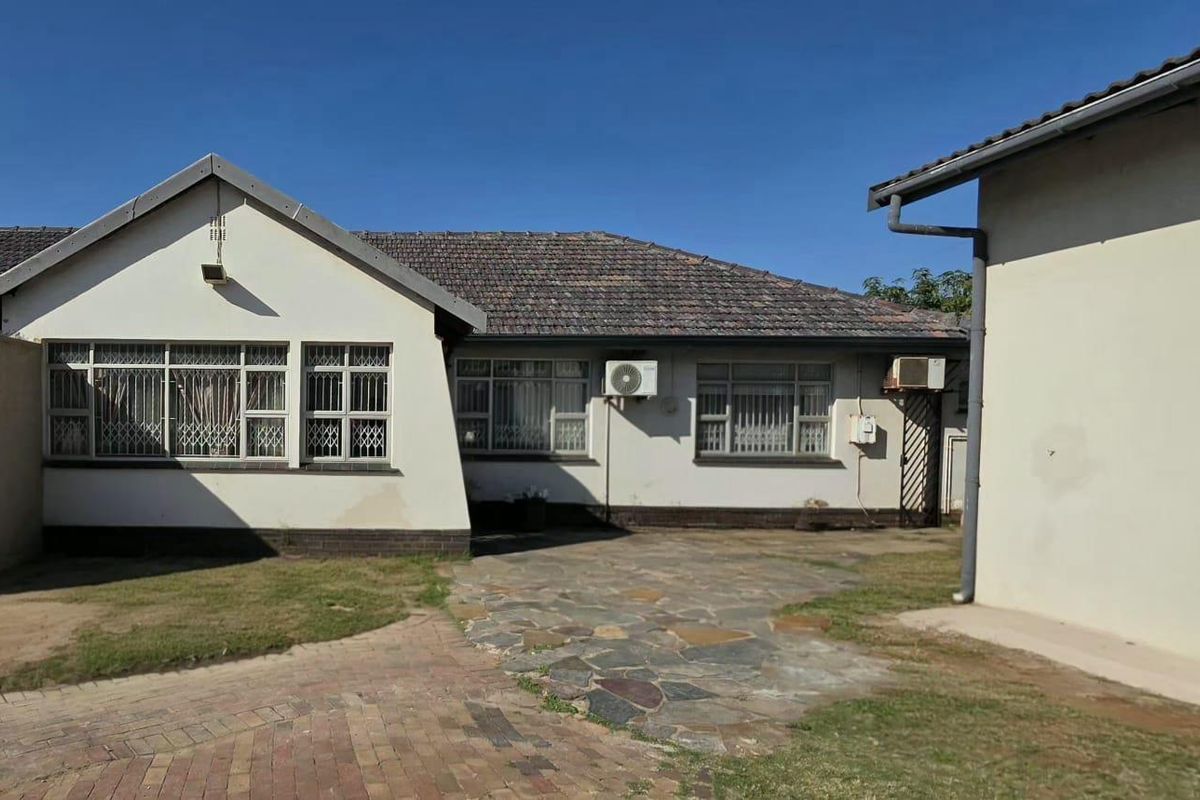 Rear view of the property featuring a tiled roof, paved walkway, and exterior wall finishes with visible signs of wear.