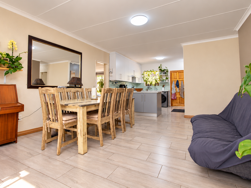 Spacious open-plan living and dining area featuring modern tiled flooring, neutral walls, and a functional kitchen with built-in cabinetry and island.