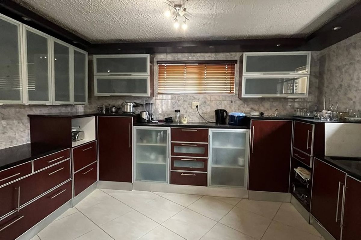 A functional kitchen featuring dark wood-toned cabinetry, tiled flooring, and ample storage space with frosted glass accents, offering a classic layout.