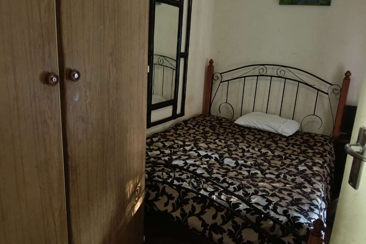 A compact bedroom featuring a built-in wardrobe and space for a double bed, requiring cosmetic updates to the wall finishes.