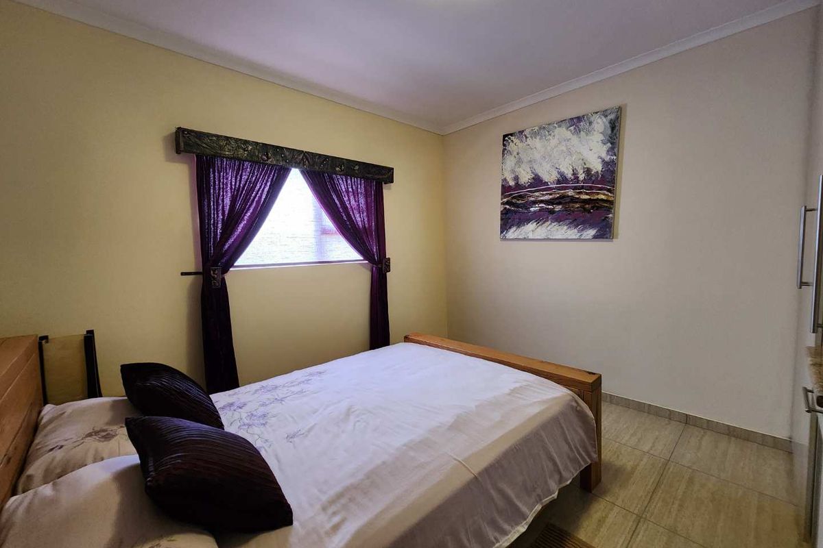 A well-maintained bedroom featuring tiled flooring, neutral wall tones, and a window with decorative pelmet and curtains.