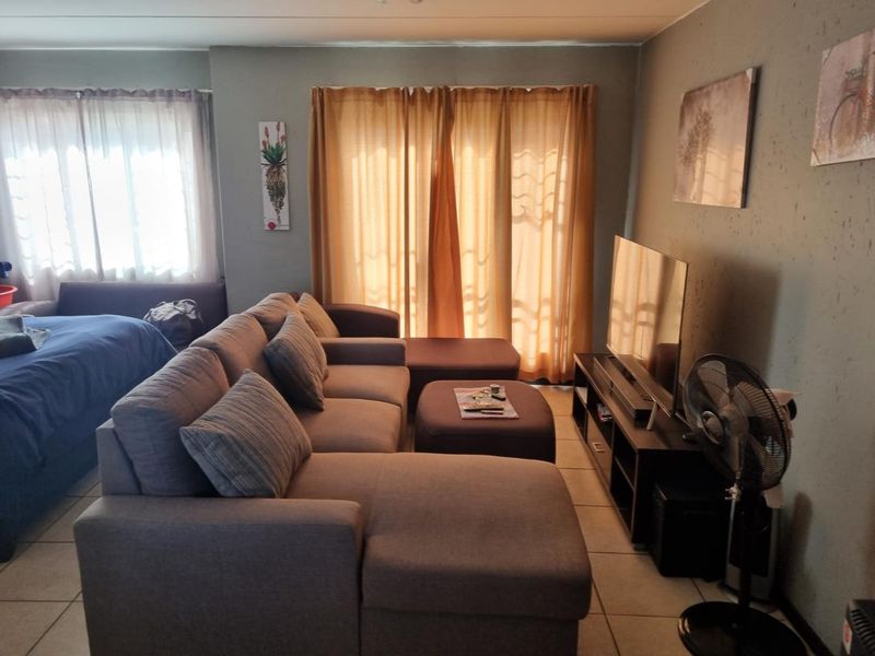 A living room area featuring tiled flooring and a sliding glass door leading to an outdoor space, with visible wall surface wear.