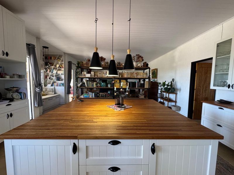 Spacious kitchen featuring a large central wooden island, white cabinetry, and a cozy built-in window seat area with integrated shelving.