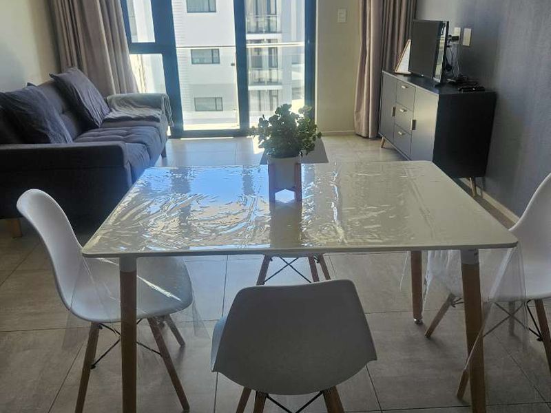 Open-plan living and dining area featuring large format floor tiles and a sliding glass door providing access to the balcony.