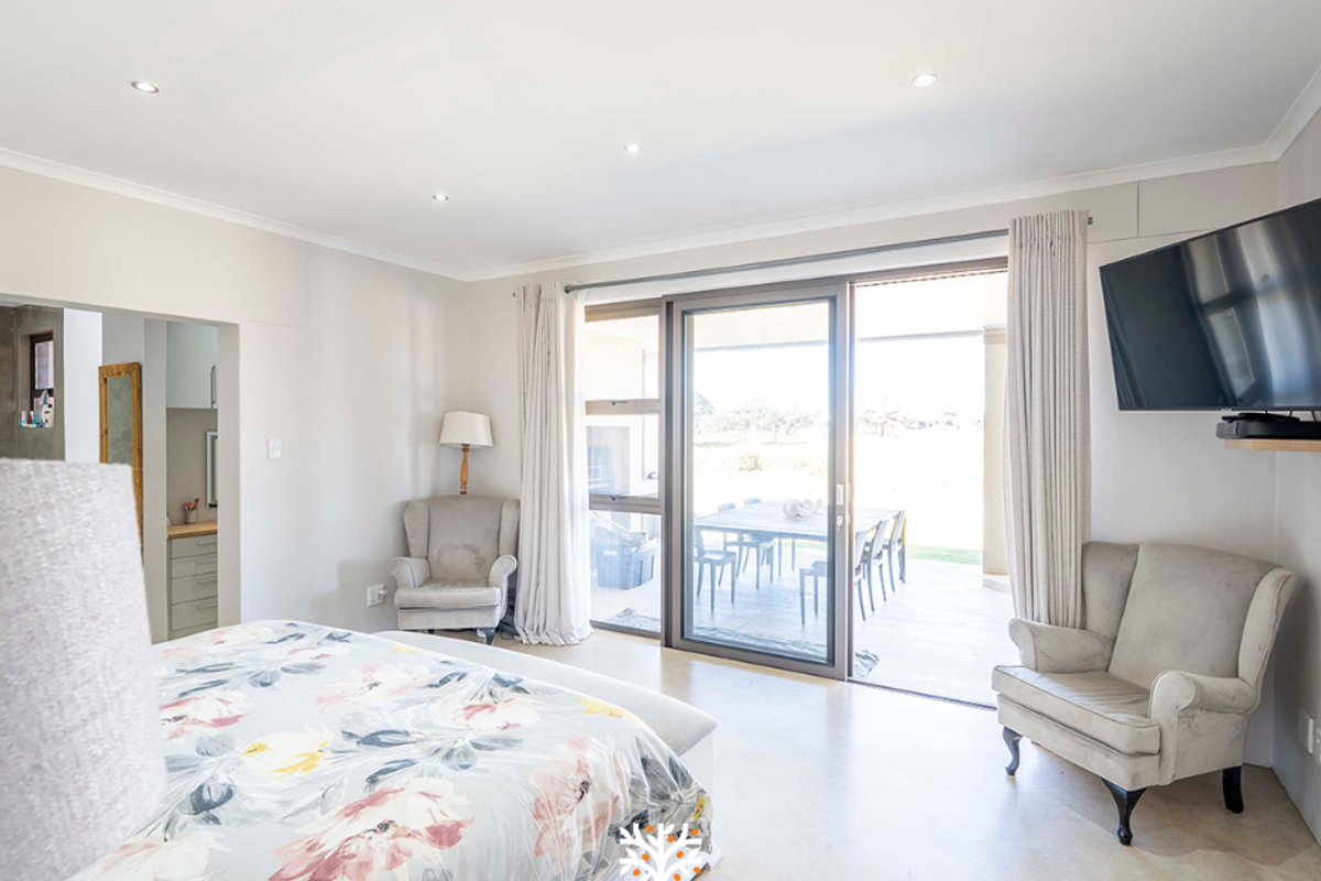 Spacious bedroom featuring polished concrete flooring, recessed downlighting, and large sliding glass doors providing direct access to an outdoor patio area.