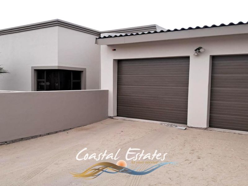 Front view of the property featuring a double garage with modern roller shutter doors and a clean, neutral exterior facade.