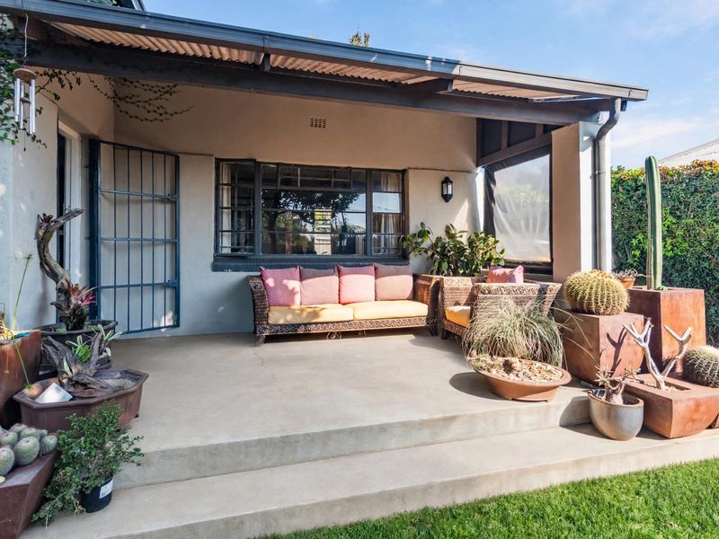 A covered outdoor patio area featuring concrete flooring, steel window frames, and a security gate, providing a pleasant space for outdoor relaxation.
